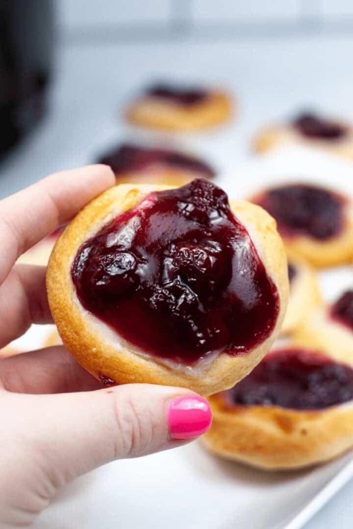 A hand holding an air fryer cherry danish.