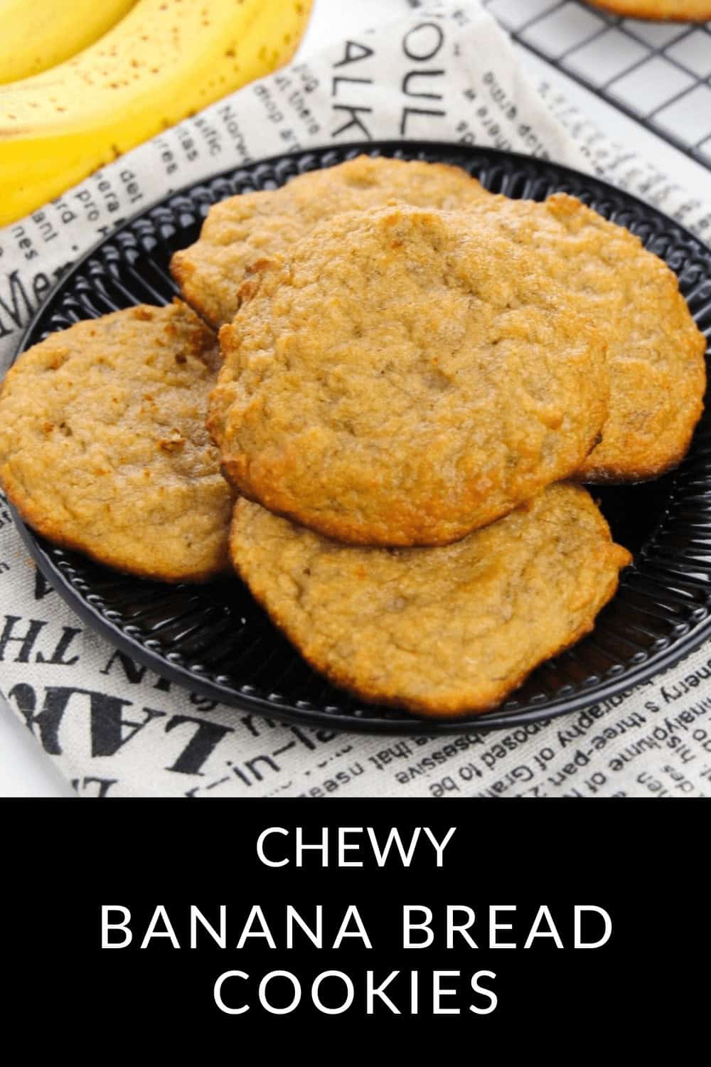 A black plate showcasing chewy banana bread cookies rests on a newspaper-style cloth. Indulge in the delightful fusion of rich banana bread flavor with the irresistible chewiness of cookies.