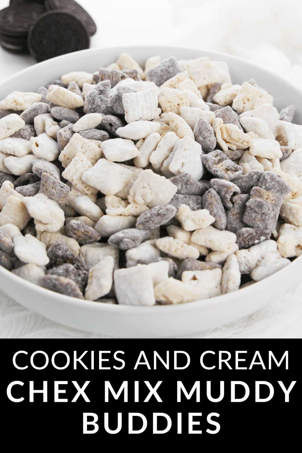 A bowl of Cookies and Cream Chex Mix Muddy Buddies, featuring cereal squares coated in powdered sugar, rich chocolate, and crunchy cookie crumbs.