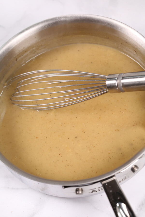 Whisking turkey gravy in a stainless steel pan.