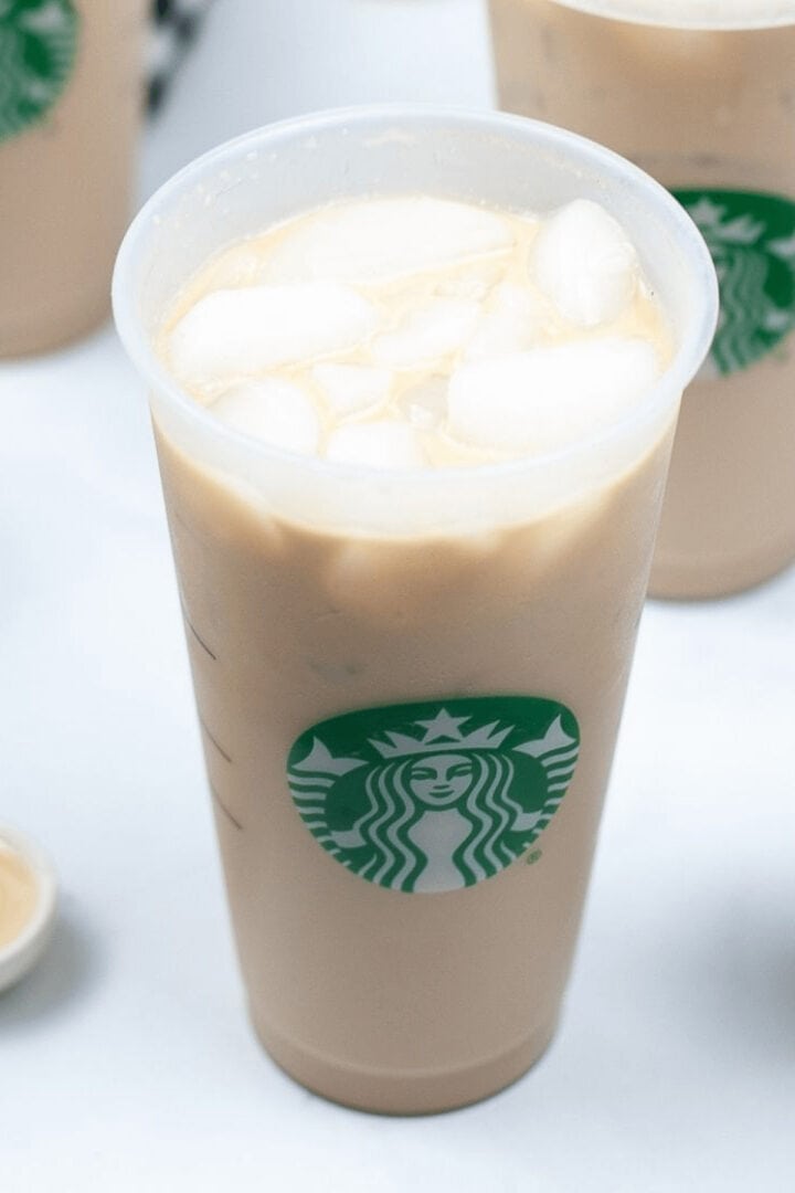 A plastic cup filled with Iced White Chocolate Mocha from Starbucks, featuring the iconic green siren logo on the front.