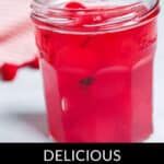 A glass jar brimming with vibrant moonshine cherries, each a burst of bright red allure.
