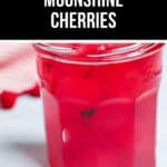A glass jar brimming with vibrant red cherries in liquid, proudly labeled "Moonshine Cherries," adds a touch of luscious indulgence.