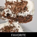 A slice of Oreo Dump Cake, adorned with a layer of white frosting and a generous crumbling of Oreo bits on top, is elegantly lifted from the baking dish.