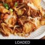 A plate of loaded tater tots topped with pulled pork, melted cheese, barbecue sauce, pinto beans, and green onions—this totchos recipe is the ultimate comfort food.