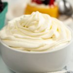 White bowl filled with whipped cream on a marble table.