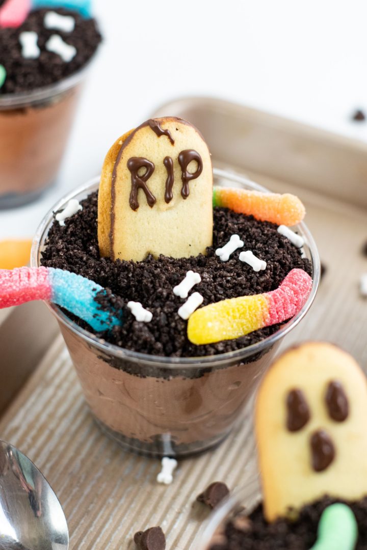 Halloween dirt pudding cup with cookie tombstone and gummy worms. 