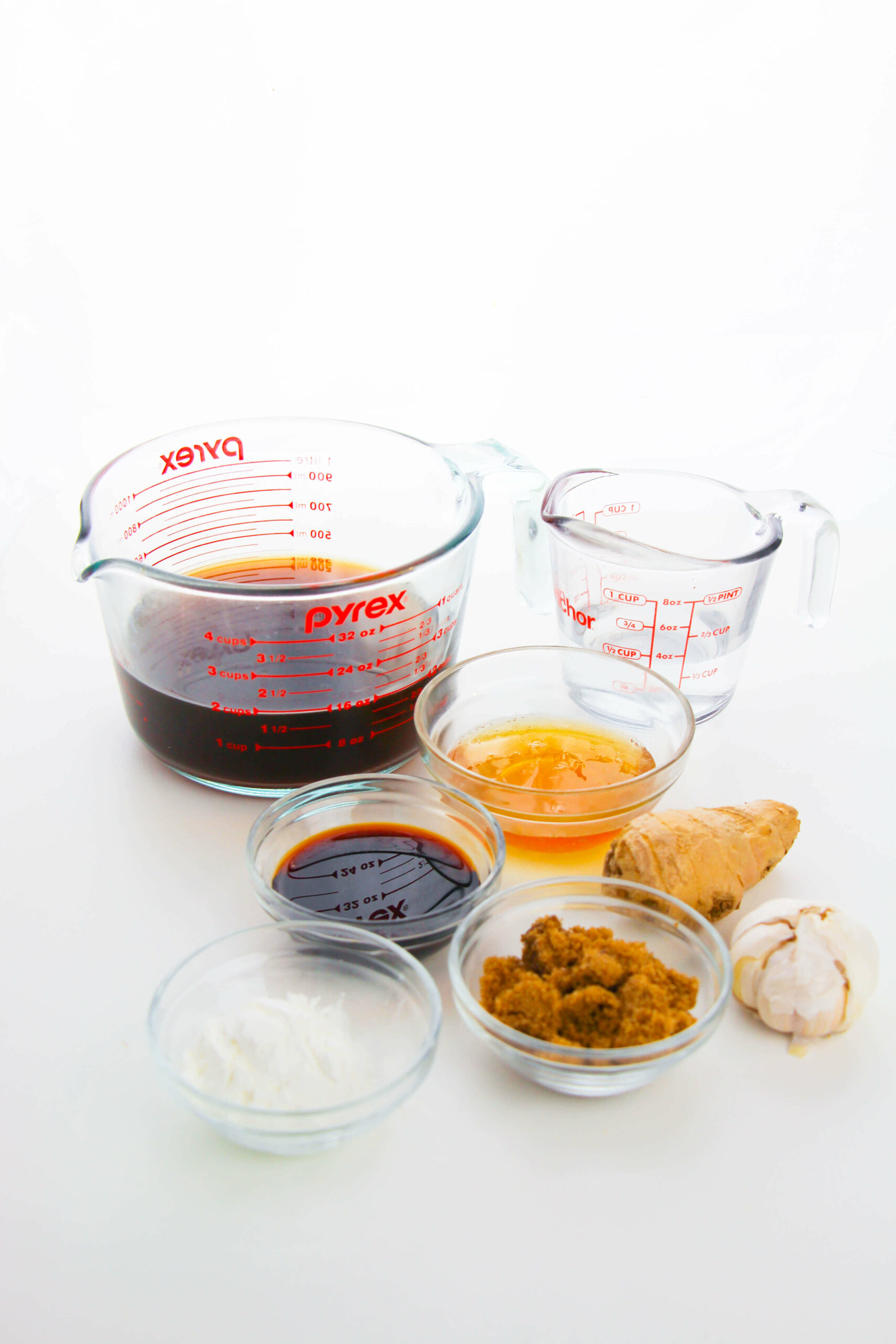 Various ingredients measured out in glass containers on a white background.