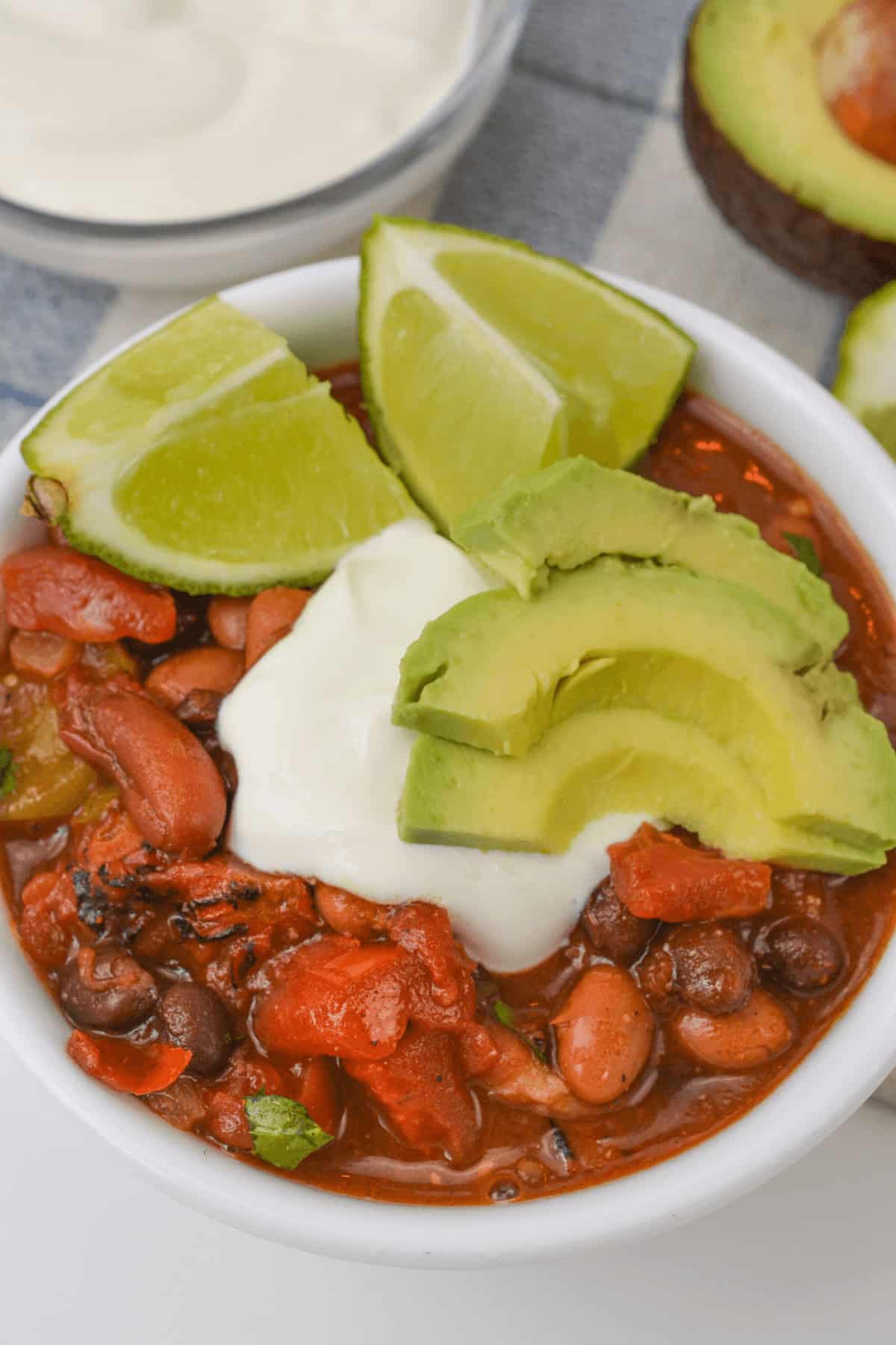 A bowl topped with avocado slices, lime wedges, and a dollop of sour cream.