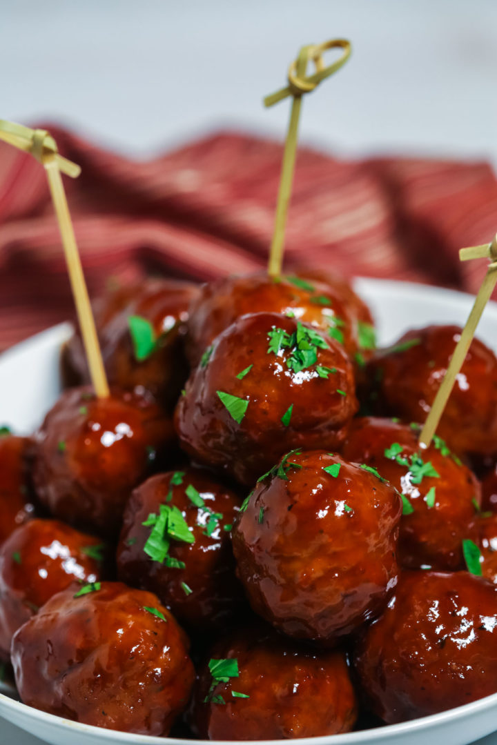 BBQ Crockpot meatballs in a white bowl with toothpicks