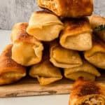 Buffalo Chicken Spring Rolls stacked on a wooden cutting board.