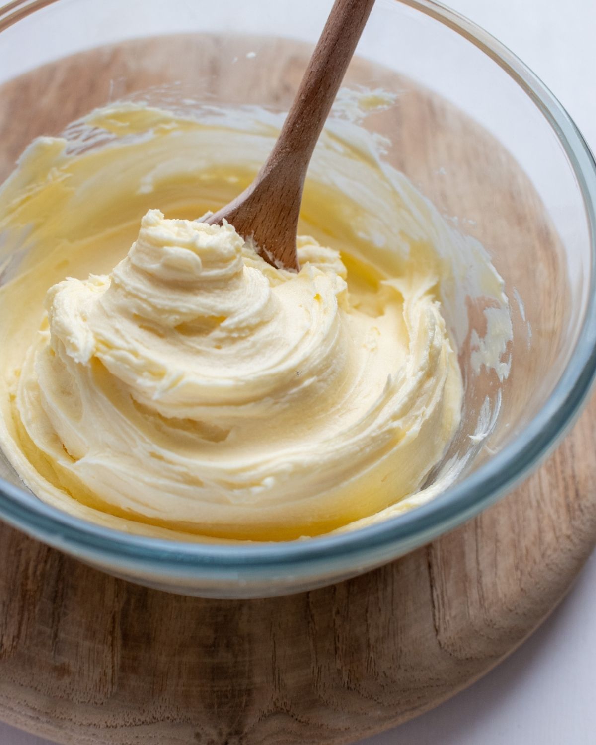 Buttercream frosting for cookies in a bowl with a wooden spoon