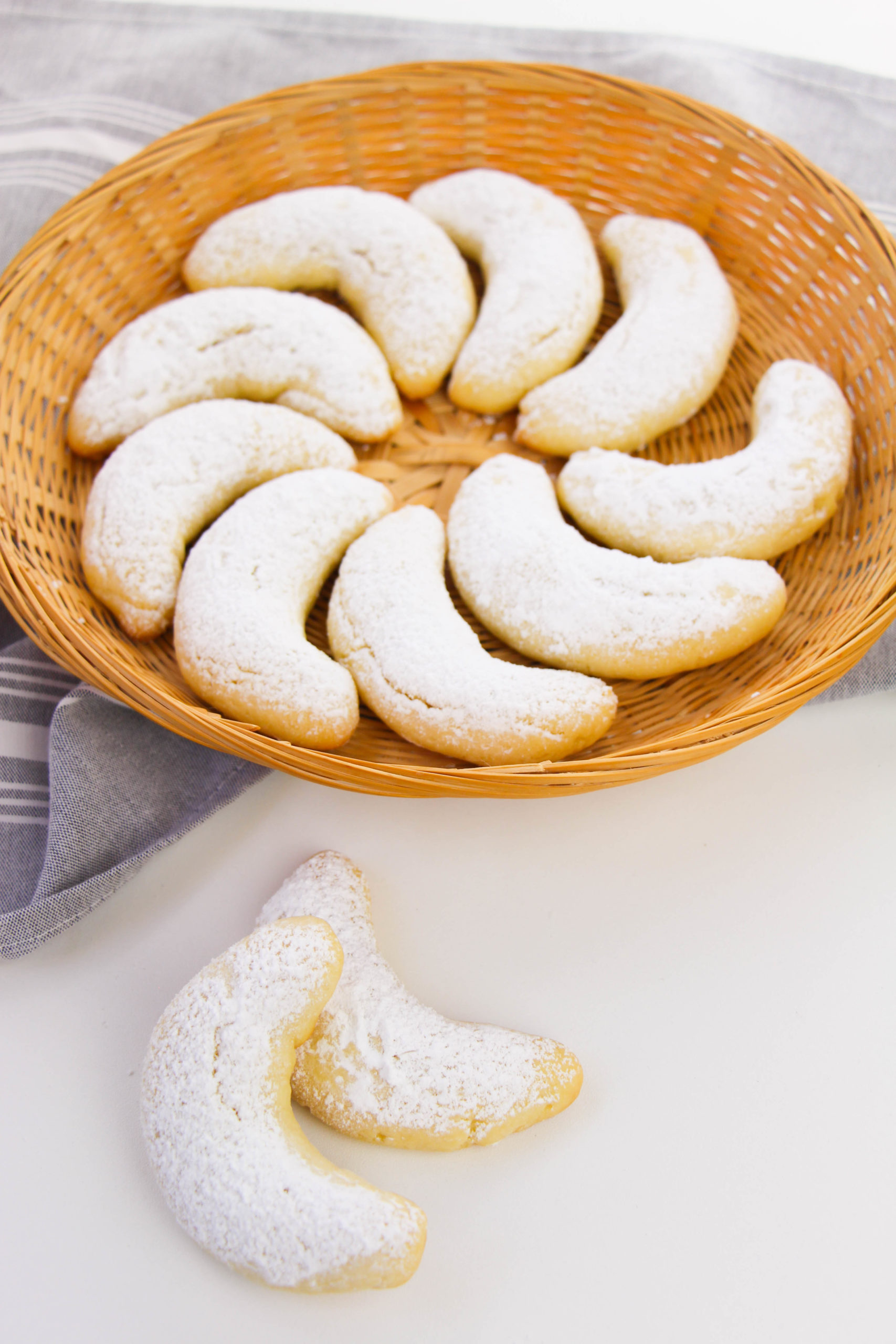Almond crescent cookies arranged on a wicker plate 