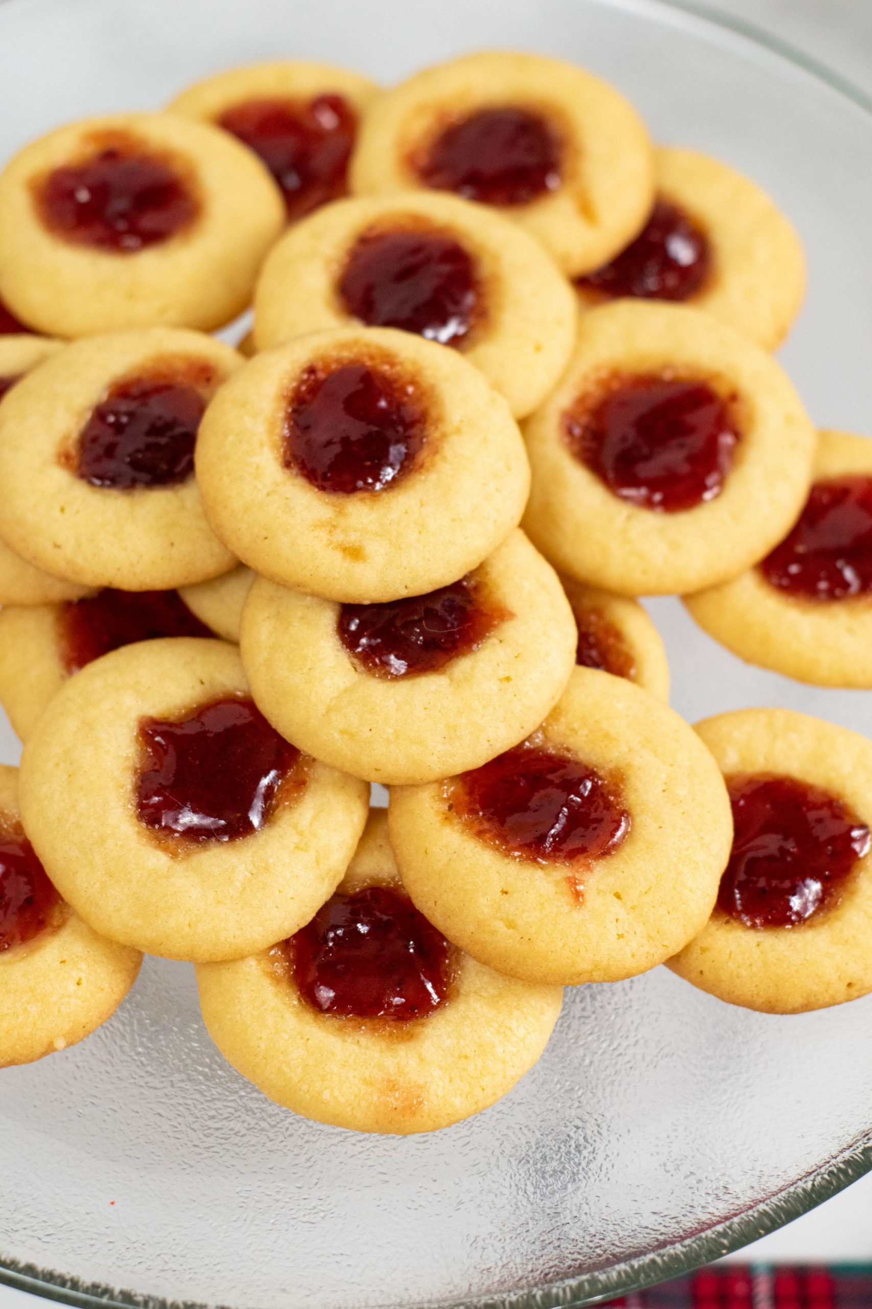 A pile of raspberry thumbprint cookies on a plate 