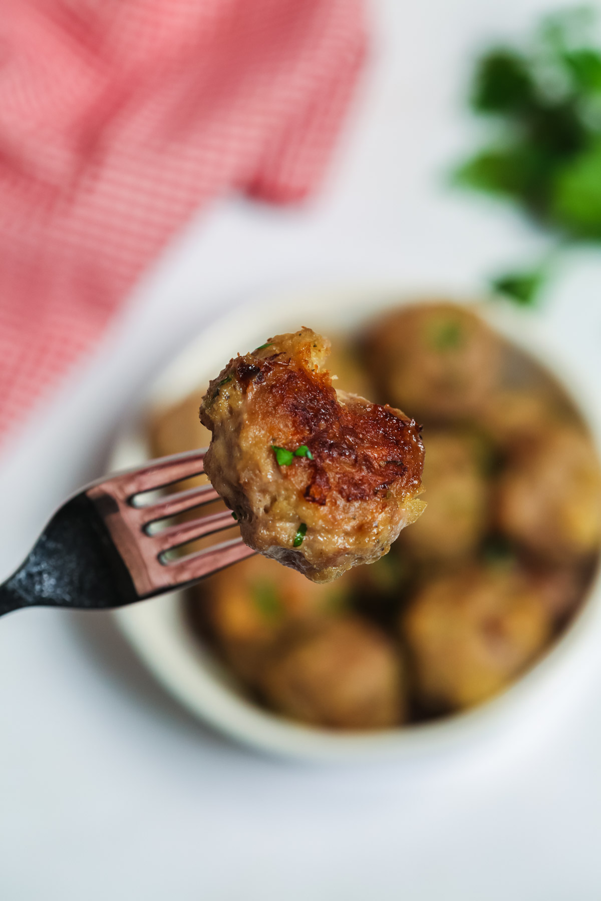 A single Italian baked meatball on a fork. 