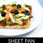 A slice of sheet pan Mexican pizza recipe topped with ground meat, lettuce, tomatoes, and black olives on a white plate.