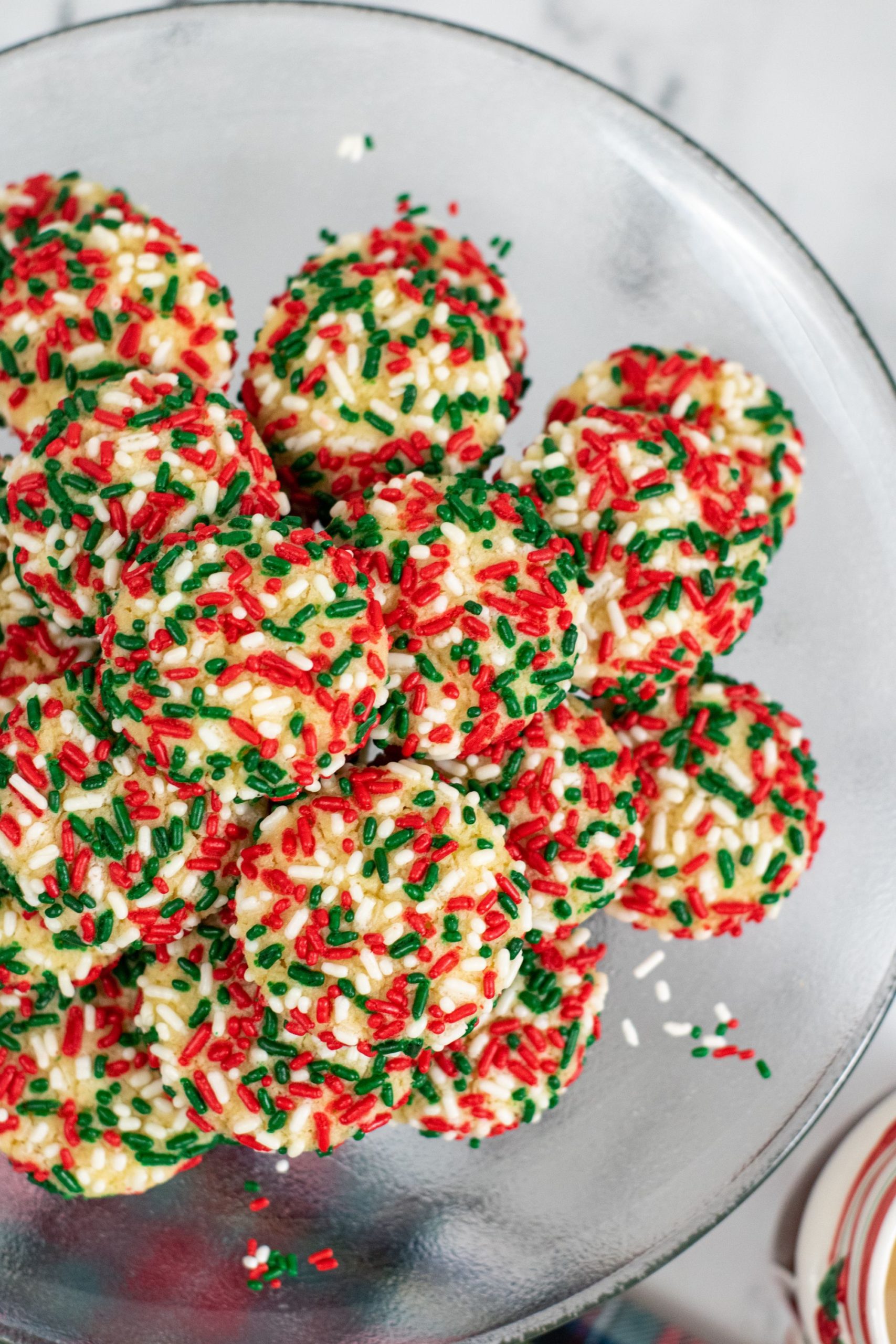 a pile of christmas sugar cookies with sprinkles on a plate
