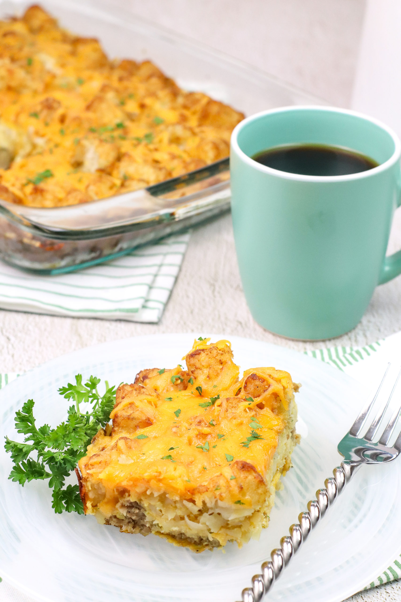 Tater Tot Sausage Breakfast Casserole on a plate with a cup of coffee