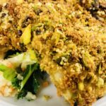 Pistachio Crusted Fish on a white plate on salad.