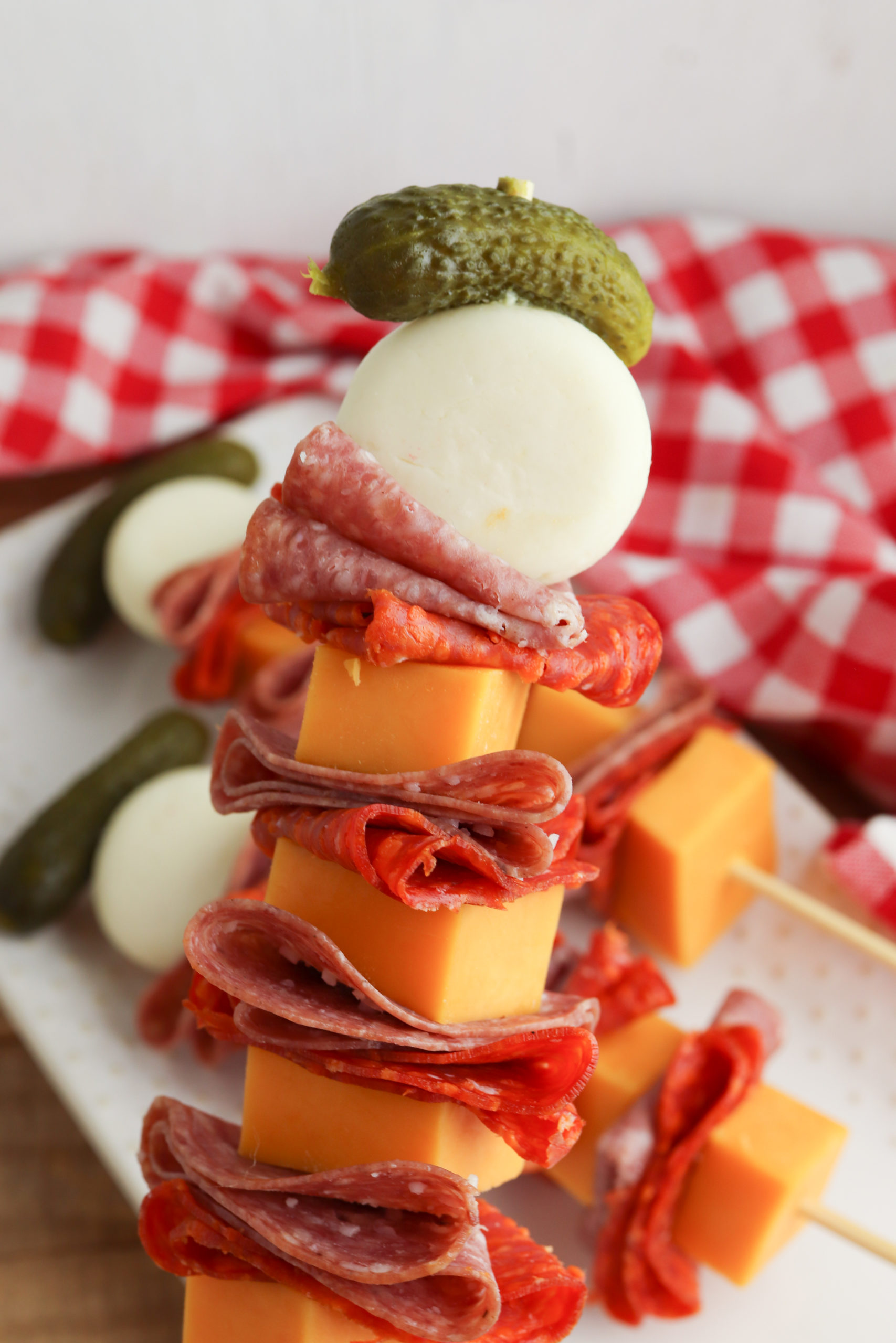 Charcuterie Skewers stacked high with a red and white checked napkin.