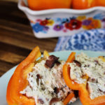 Bacon Ranch Chicken Stuffed Bell Peppers cut in half with additional stuffed peppers in a casserole dish in the background.