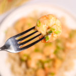 A fork of Creamy Garlic Shrimp and Rice with a dish of Creamy Garlic Shrimp and Rice in background.