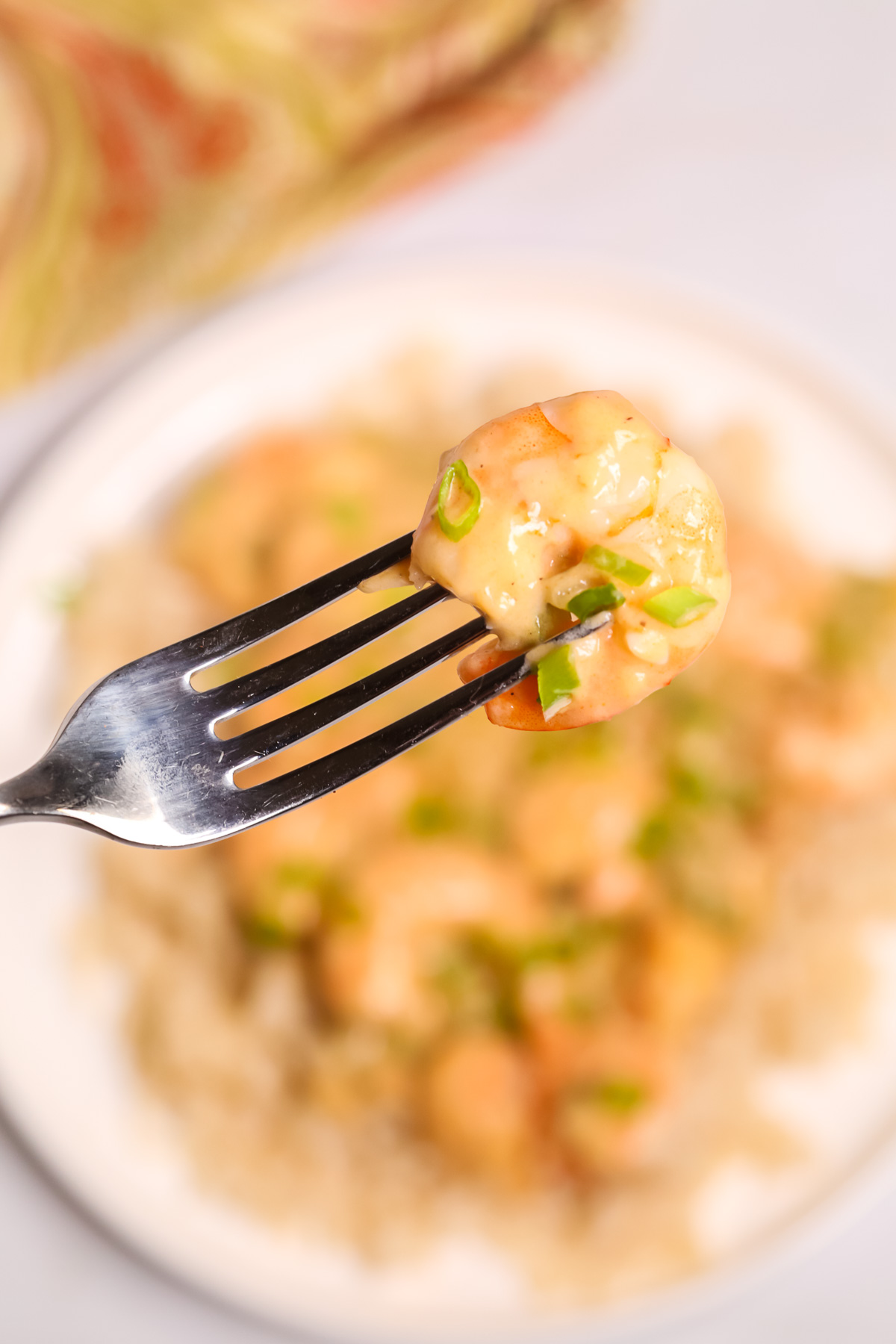 A fork of Creamy Garlic Shrimp and Rice with a dish of Creamy Garlic Shrimp and Rice in background.