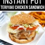An Instant Pot Teriyaki Chicken Sandwich with lettuce, tomato, and cheese on a sesame bun is served on a white plate, accompanied by sweet potato fries in the background.