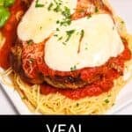 A classic Veal Parmesan plate, topped with melted cheese and tomato sauce, served over a bed of spaghetti and garnished with chopped parsley.