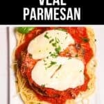 A classic Veal Parmesan plate topped with melted cheese and tomato sauce, served over spaghetti and garnished with chopped parsley for a flavorful Italian favorite.