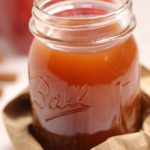 Apple pie moonshine in a mason jar wrapped in a paper bag.
