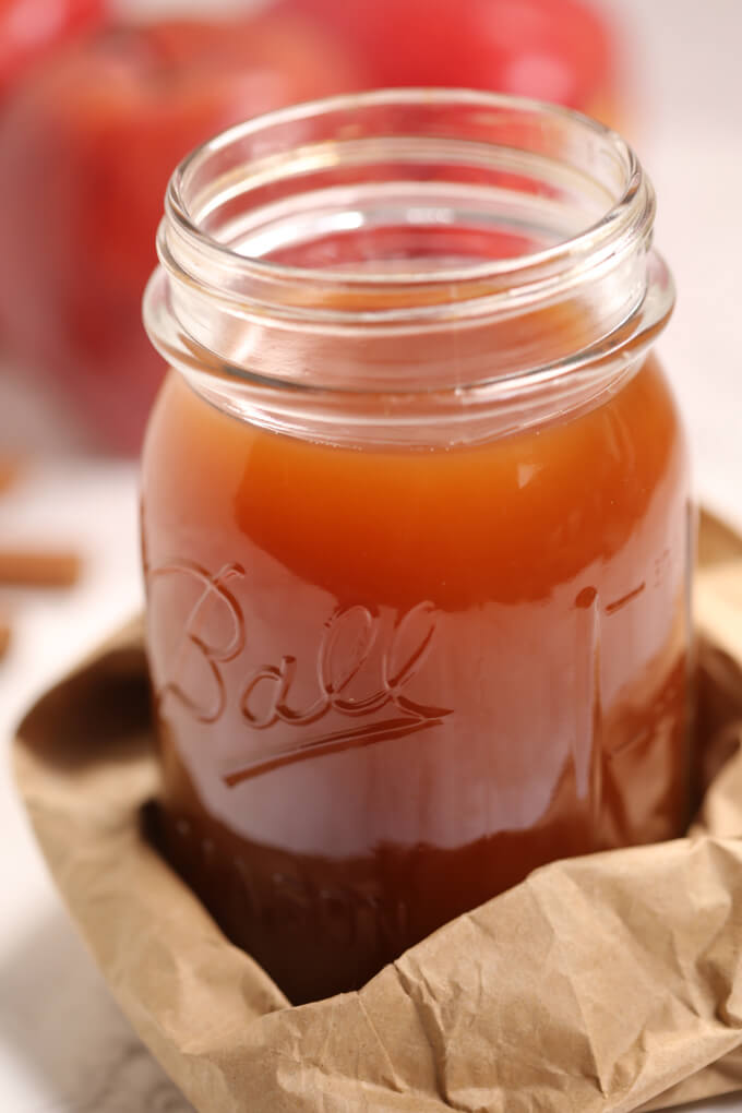Apple pie moonshine in a mason jar wrapped in  a paper bag.