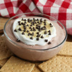 Side view of a bowl of chocolate dip with graham crackers on the side.