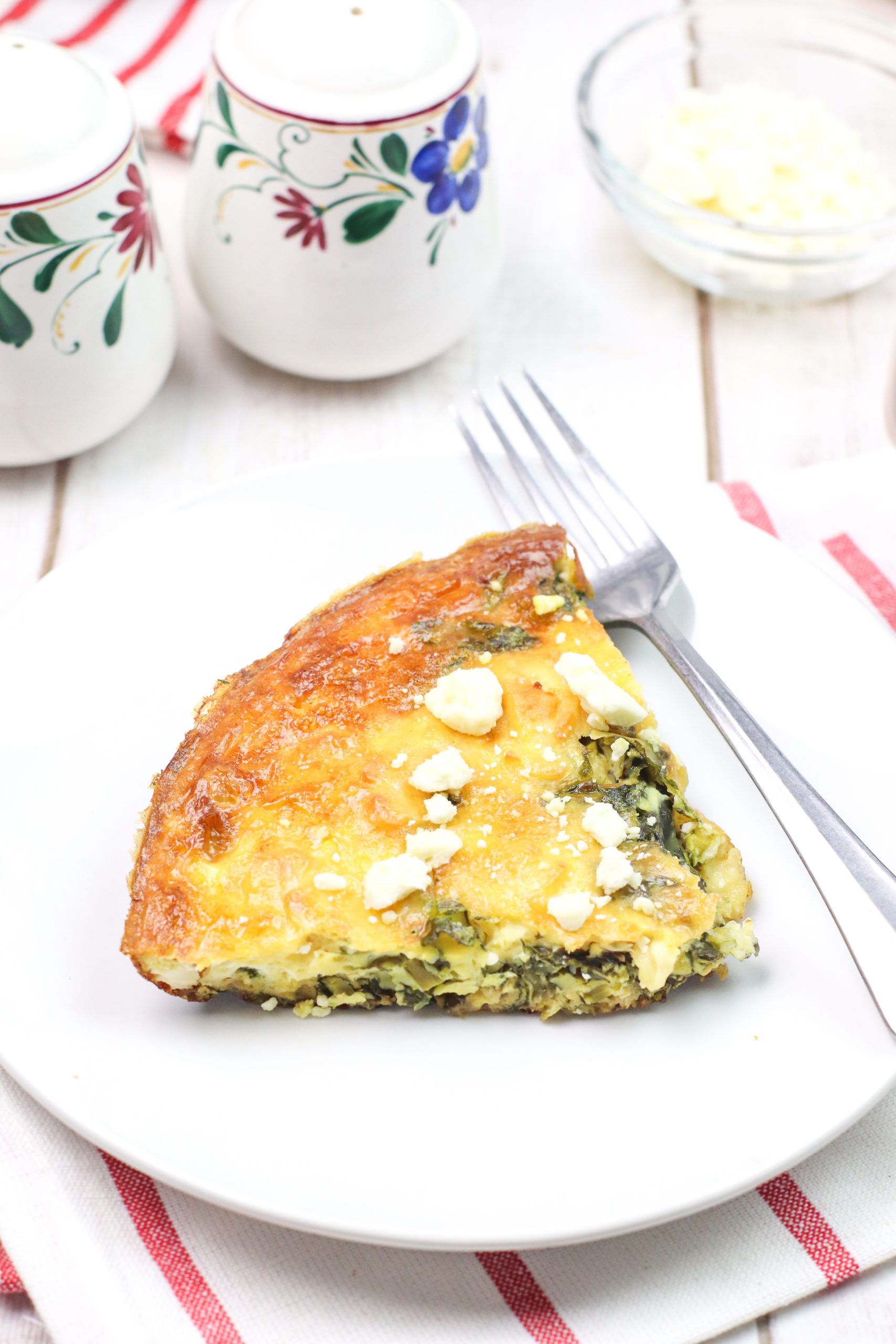 Frittata with Spinach and Feta on a white plate with a stripped placemeat.