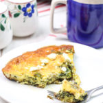 Frittata with Spinach and Feta on a white plate with a piece broken off with a fork.