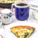 Frittata with Spinach and Feta on a plate with a cup of coffee and other breakfast items.
