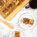Hazelnut Brownie Blondies on white plates with a full pan in the background.