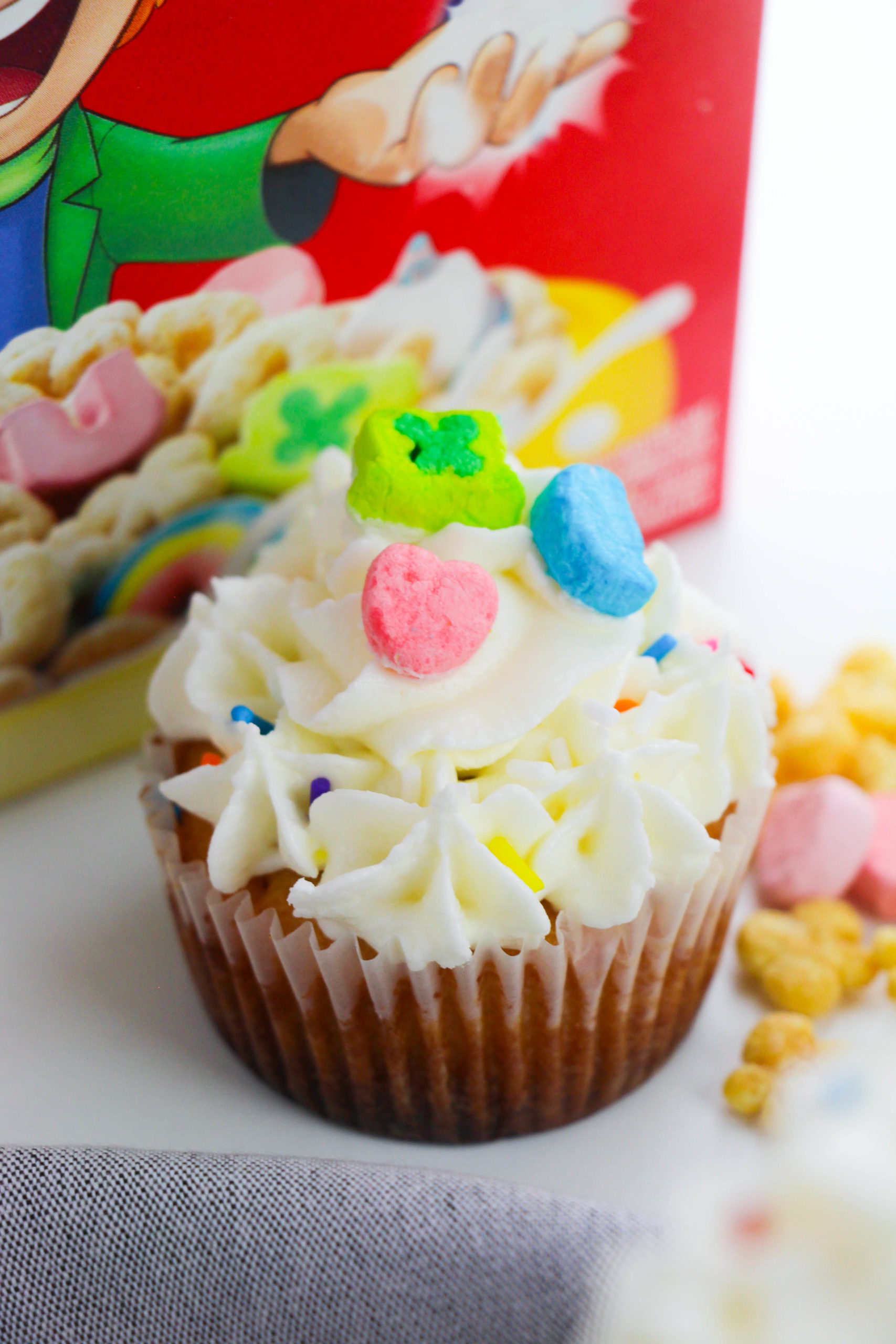 Lucky Charm Cupcakes with lucky charms box in background.