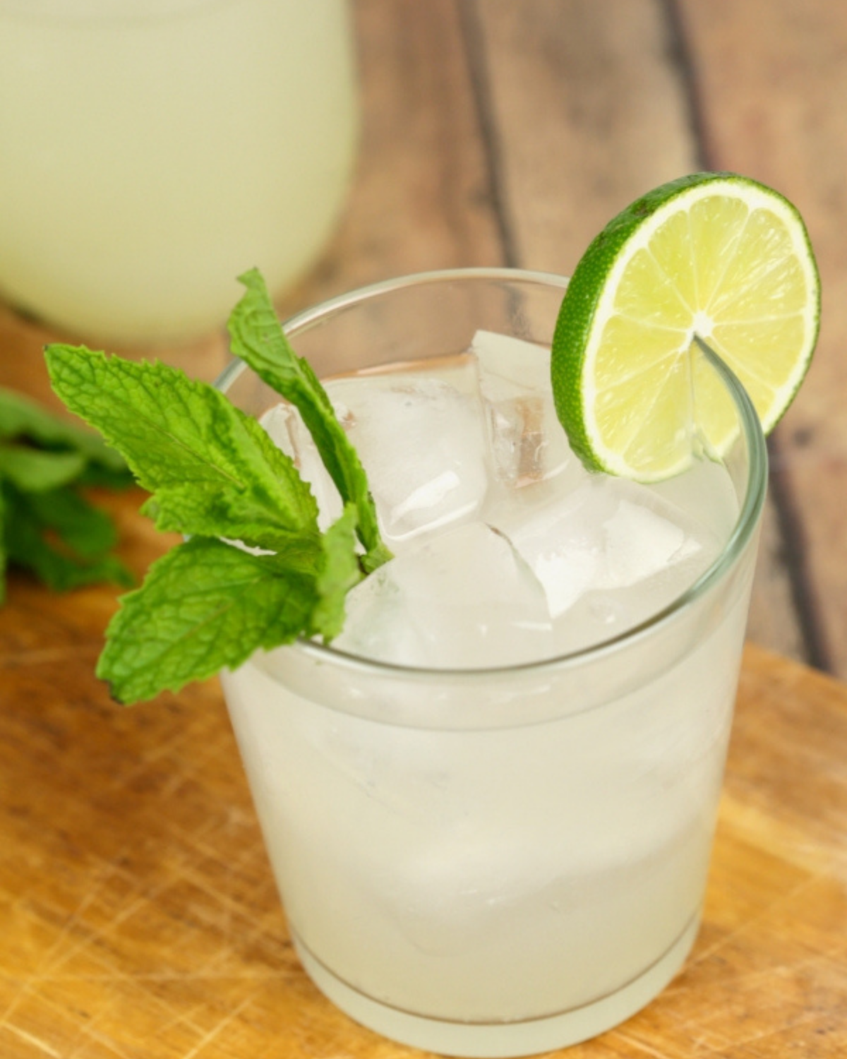 Mojito flavored moonshine in a glass with a mint sprig and lime.