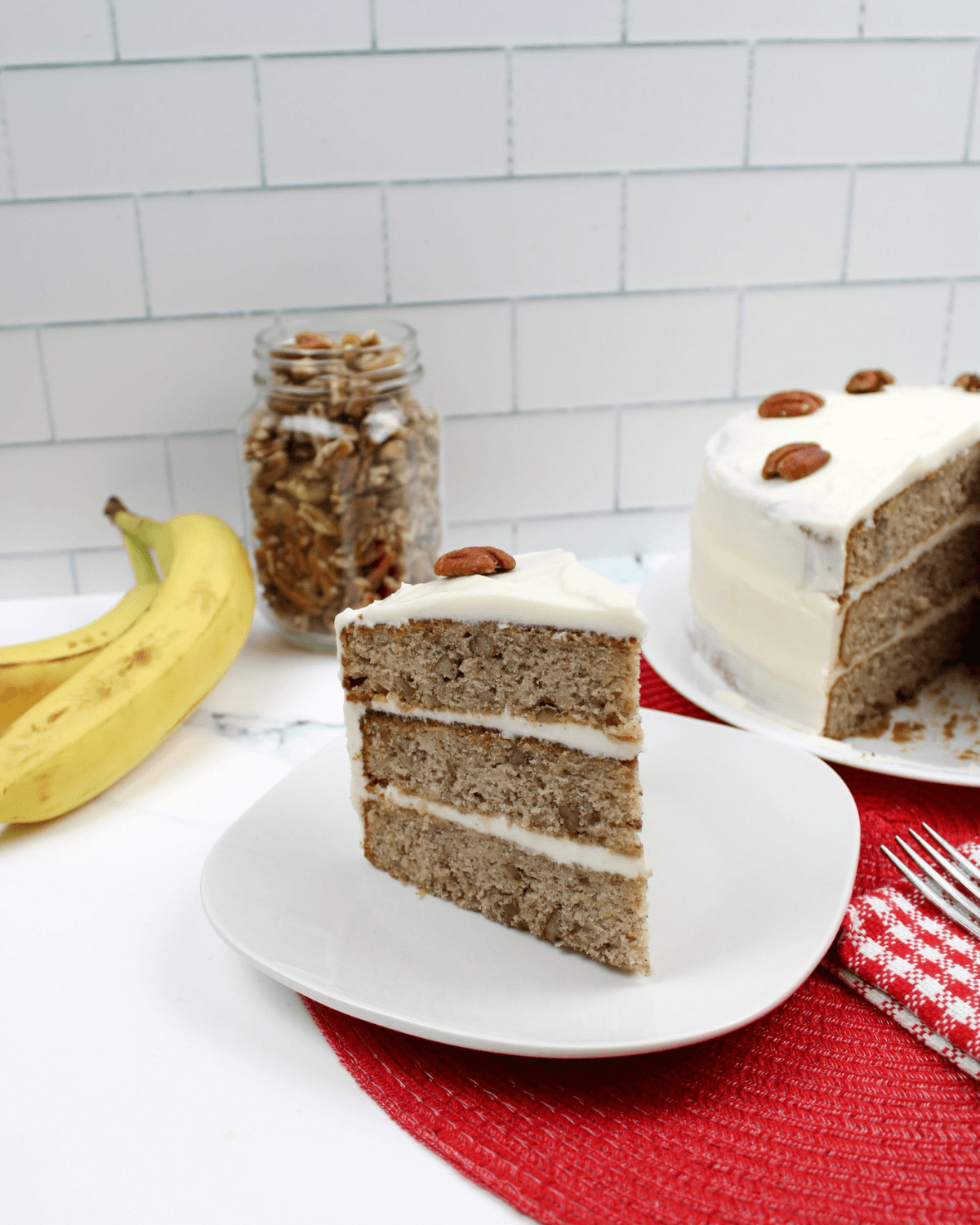 A slice of the Old fashioned hummingbird cake recipe with a whole cake in the background.