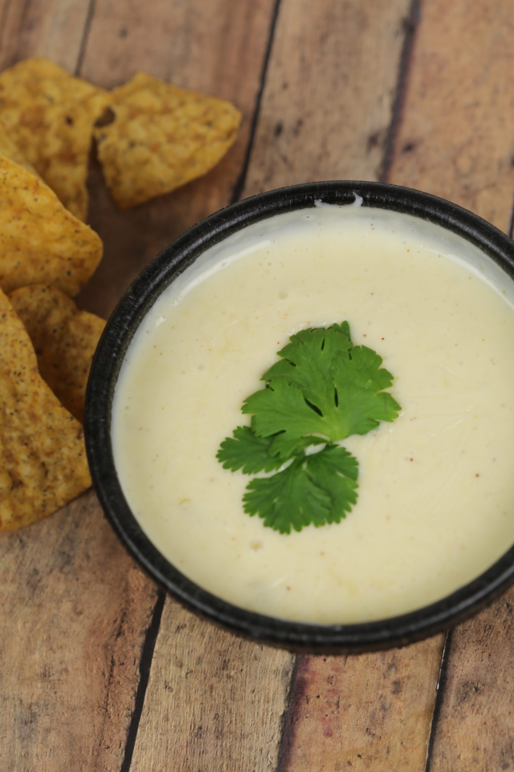 Queso Blanco Dip in a black bowl with a piece of queso in it.