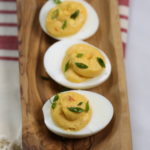 Sriracha Spicy Deviled Eggs on a wooden dish.
