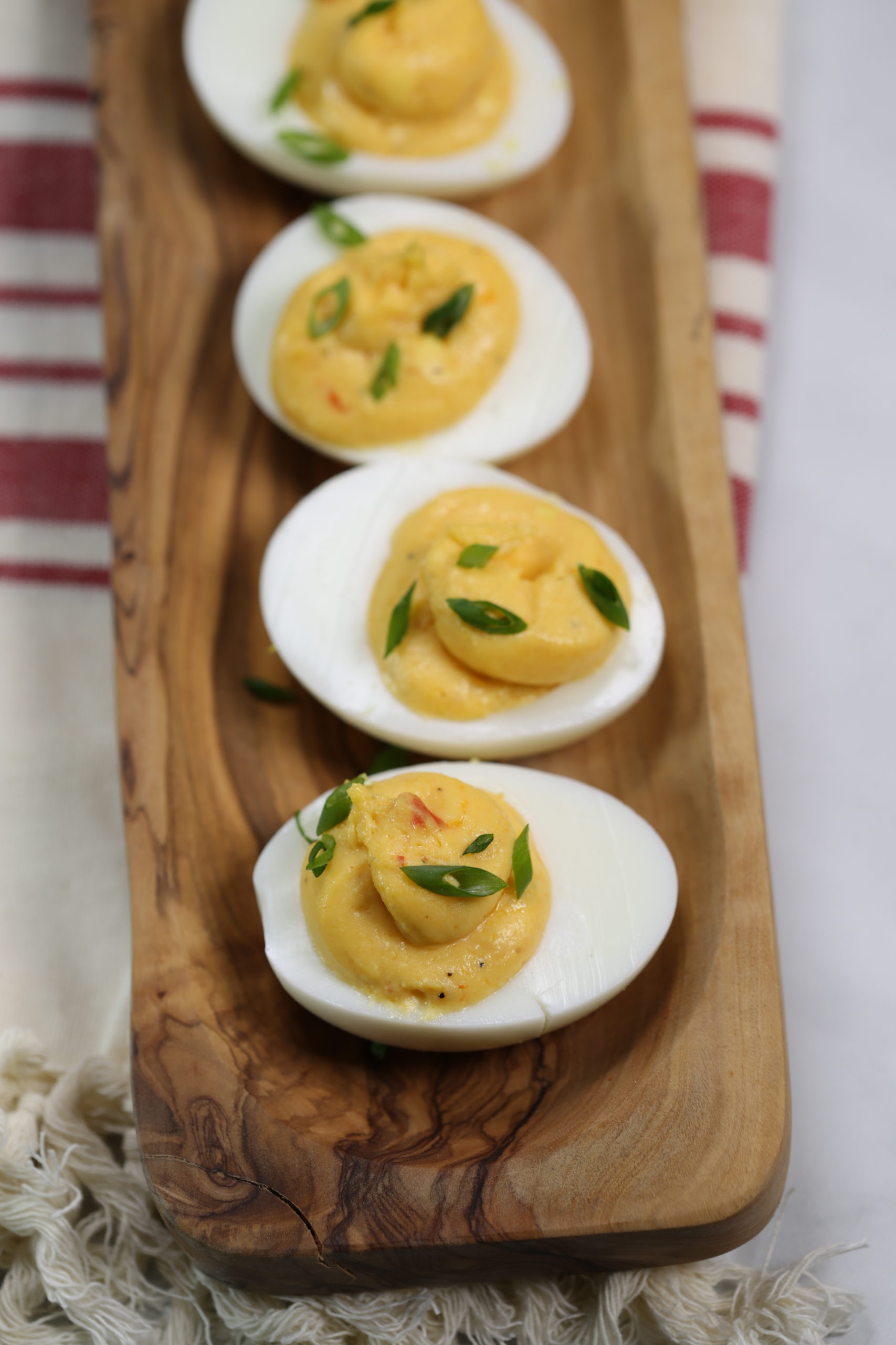 Sriracha Spicy Deviled Eggs on a wooden dish.