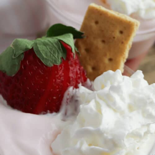 A strawberry pudding parfait with a cookie and strawberry on top.