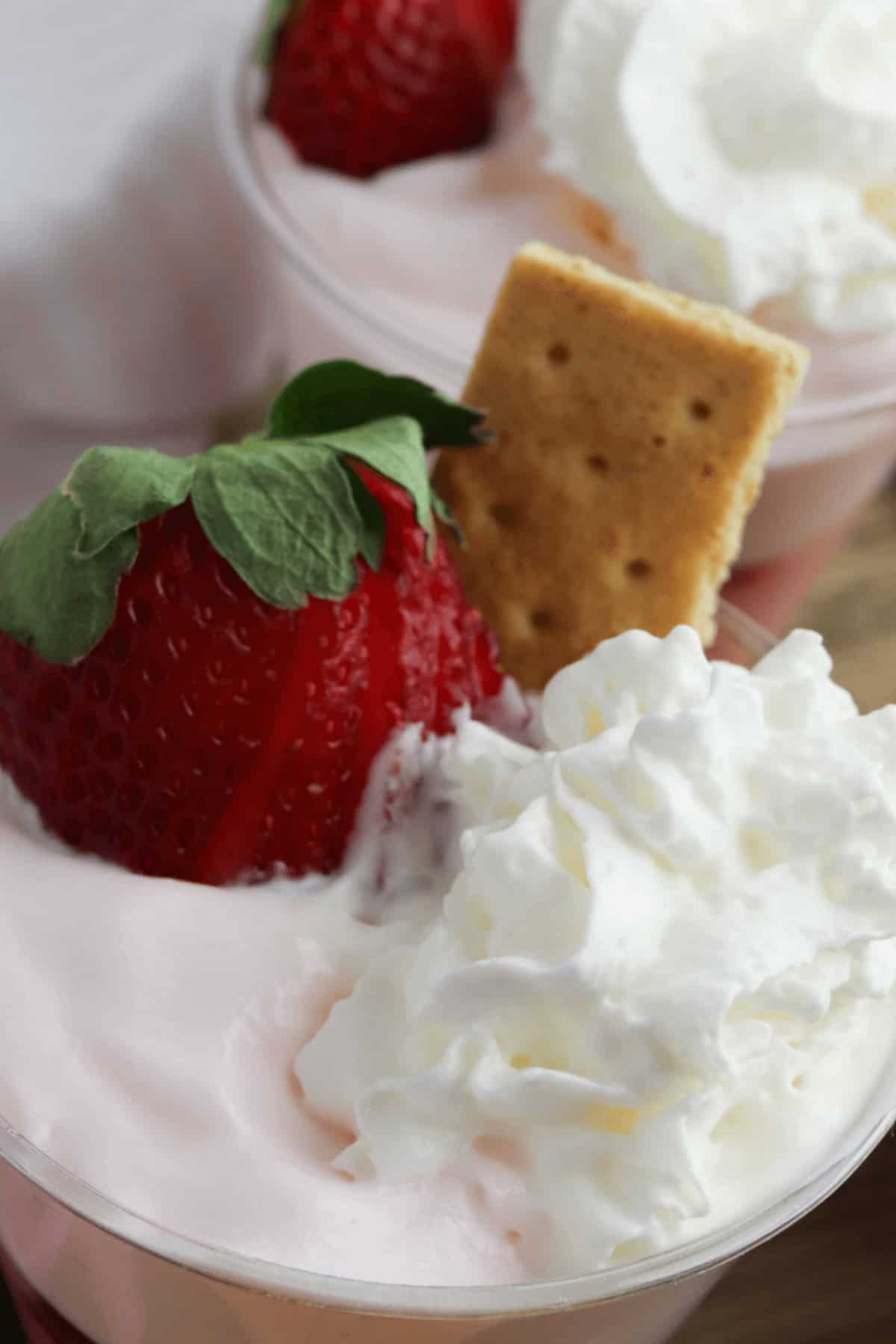 A strawberry pudding parfait with a cookie and strawberry on top.
