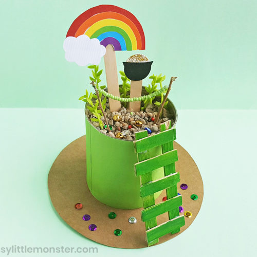 Tin can decorated with green paper, rainbows and gold.