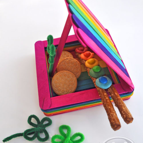 Rainbow colored popsicle craft sticks crafted together as a trap, filled with treats.
