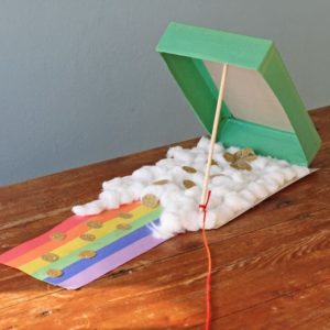 Small green repurposed cereal box decorated with a rainbow and cloud themed walkway leading up to the trap.