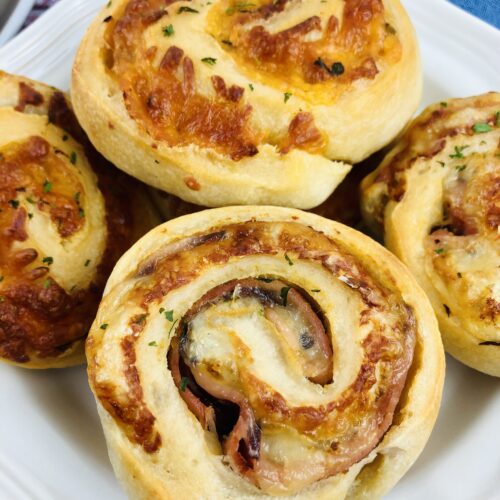 Baked Ham and Cheese Roll Ups on a white plate.