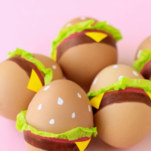 Eggs decorated to look like burgers with a bun, lettuce, and cheese.